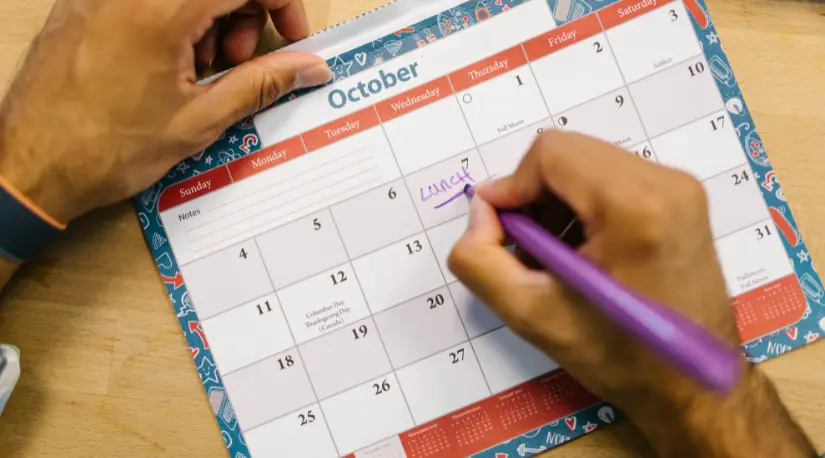 Hands marking a date on a paper October calendar