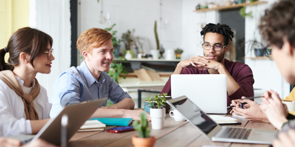 Coworkers chatting around a table with laptops