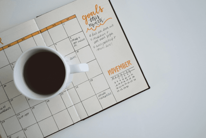 Coffee cup on an open planner with monthly goals