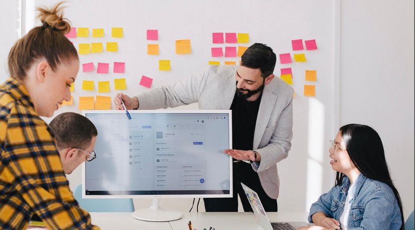Team reviewing scheduling software on office monitor