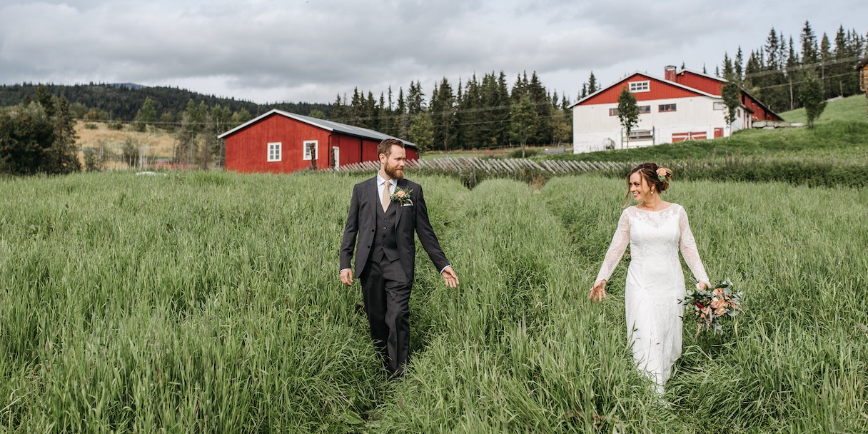 Bride and groom walking through a grassy field