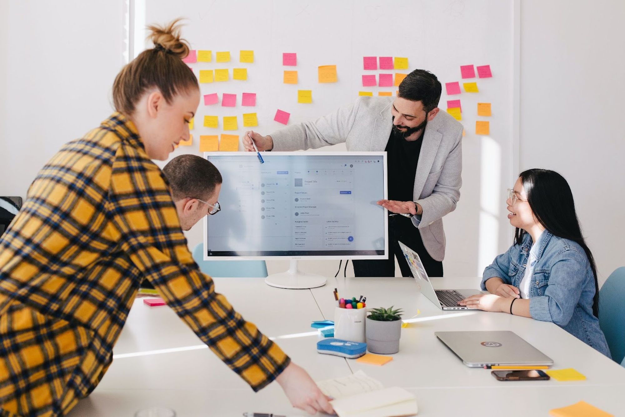 Team brainstorming with sticky notes around a monitor