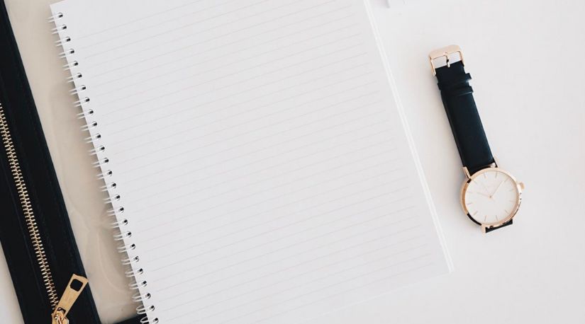 Blank notepad beside a wristwatch on a desk